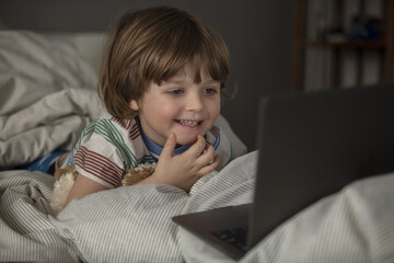 The child watches cartoons on the laptop before a sleep.Baby have a call and talking before a sleep on the the laptop. Toddler watch a movie before a sleep.