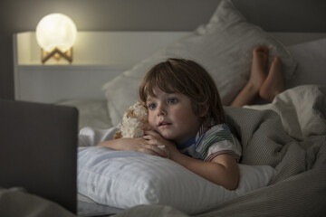 The child watches cartoons on the laptop before a sleep.Baby have a call and talking before a sleep on the the laptop. Toddler watch a movie before a sleep.