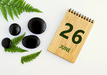 June 26. 26th day of the month, calendar date. Notepad, black SPA stoneJune s, green leaves. Summer month, day of the year concep