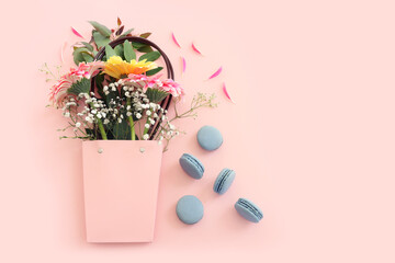 Top view of blue macaron or macaroon and flowers over pastel pink background. Flat lay