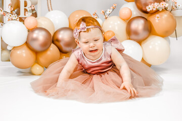 Little crying unhappy redhead baby girl celebrates first birthday anniversary. 1 year family party Professional photoshoot in photo studio. Cute adorable red hair kid in pink dress.Home children room