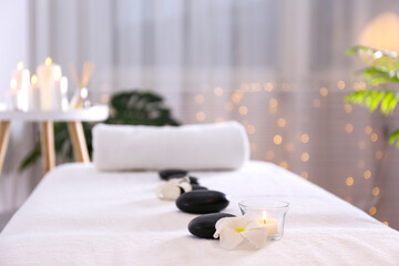 Close up shot of black volcanic stones laid in line and a rolled towel on the massage table in a...