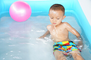 Fototapeta na wymiar Hot weather. Boy playing with water happily in the tub.