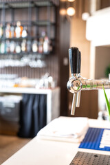 A draught beer tap at the bartender counter bar, drink equipment and object.