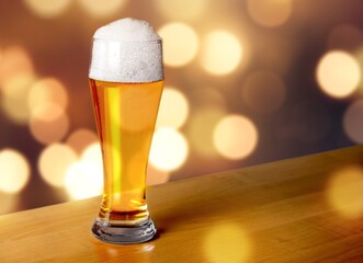 A glass of cold beer on table in bar background.