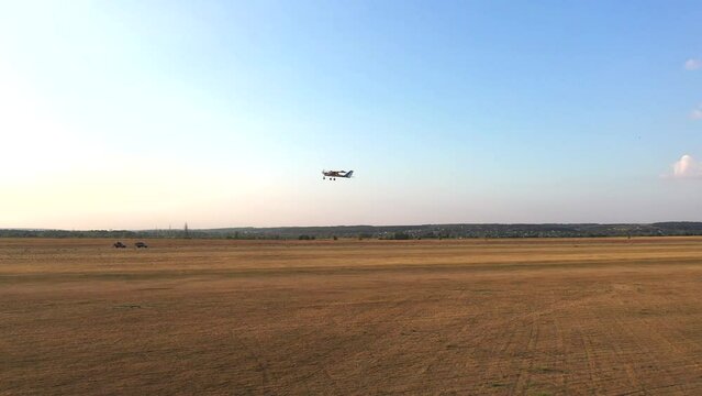 Small airplane with propeller engines flying in a clear blue sky. Aerial view to lightweight plane flight above rural airport. Travel at ultralight sport aircraft. Aviation concept. Drone shot