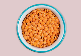 Red lentil in bowl isolated on pink background. Top view