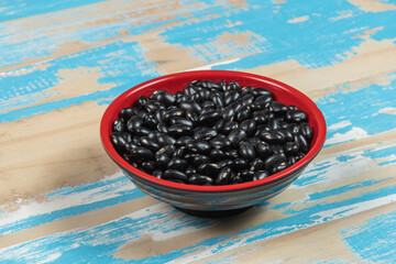 bowl with black bean beans on blue rustic wooden table, top view