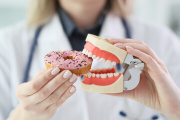 Woman imitates biting of sweet donut with human jaws model