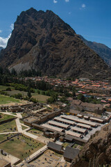 View of the entrance to the archaeological site of Ollantaytambo, the tourist market and the town with its typical houses with a big mountain in the background and a beautiful blue sky, in Peru. 