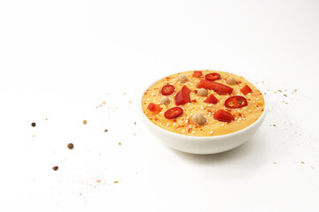 Hummus with paprika and hot pepper on a white background in a plate topped with chickpeas and sesame seeds, oil and spices. Culinary and food menu photo