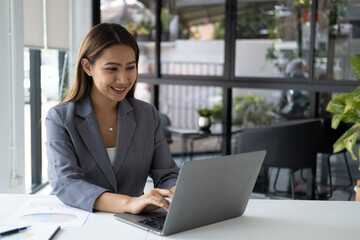 Beautiful confident businesswoman typing on laptop computer while working at her office desk.