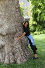 beautiful girl hug a big tree at the park, good energy