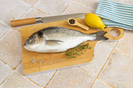 daurade enti&egrave;re, en gros plan, sur une planche &agrave; d&eacute;couper	