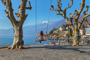 Young woman on a swing by the lake of Lago Maggiore, Ascona, Switzerland - 592323910