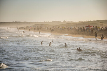 dozens of people bathing in one of the beaches of Punta del Diablo, during sunset
