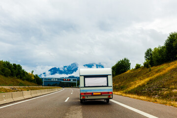 camping trailer, in the mountains on the road. camper trailer on the highway on mountain background on overcast sky