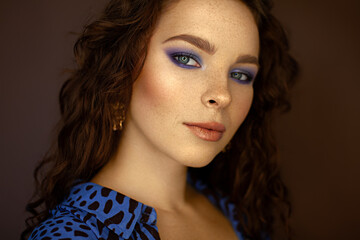 Close up of beautiful girl with curly red hair and freckles looking at camera 