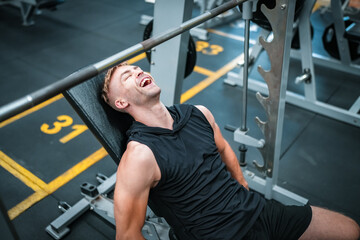 Male athlete exercising in the gym, lifting weights, pulling joints.