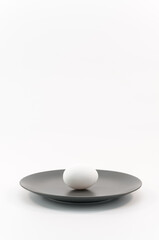 immagine con piatto in ceramica grigio e uovo bianco su superficie bianca