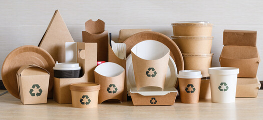 Lots of disposable paper containers and utensils with a recycling sign. Panorama. The concept of...