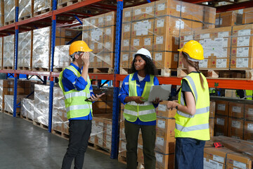 Multiethnic industrial workers checking their logistic lists while working with transportation of goods in warehouse