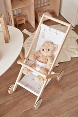 Fototapeta na wymiar Children's educational wooden toys. Nursery decor. Scandinavian style playroom. Wooden stroller