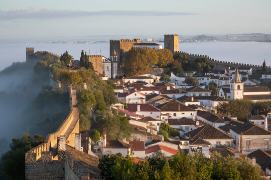 View over the old town and walls of Obidos in morning mist, Obidos, Centro Region, Estremadura, Portugal