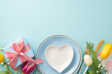 Fototapeta na wymiar Modern Mother's day table setting concept. Top view flat lay of empty plates, cutlery, tulips, gift box, postcard on pastel blue background. Empty space for text or advert