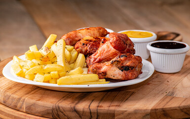 bbq chicken wings with french fries and ketchup, mustard and bbq on a rustic wooden table on a black background