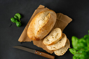 Crispy Bread and kitchen knife, basil on a black background. Sliced fresh white bread. Food...