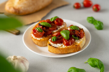 Bruschetta with Ricotto cheese and cherry Tomatoes, basil, garlic on a grey concrete background. Food. Food background. Close-up