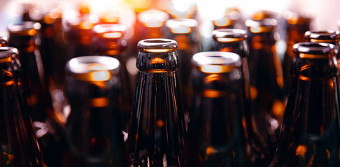 Banner Brewery plant production line with Glass bottles of beer on dark background with sun light