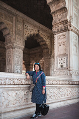 Indian girl standing beside a white marble structure with decorated pillars and arches inside the Red fort Delhi. Single tourist at the Hall of private audience also known as the diwan-i-Khas.