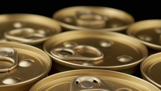 Close up, Rotation of Metal Cans with Canned Food or Pate on Black Background. Angle top view. Golden cans with pull rings. Canned tourist food or wet pet food. Military, humanitarian aid to soldiers.
