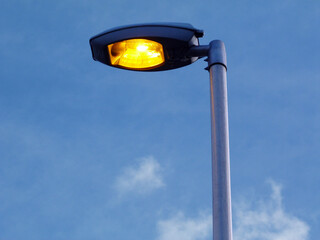 Modern oval halogen street lamp head with warm yellow light. Abstract view in diminishing...
