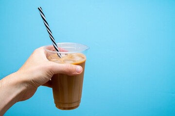 Closeup shot of a hand holding an iced coffee in a plastic takeaway cup