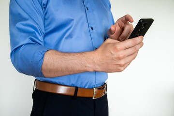 Closeup shot of a man holding a phone and pointing at the screen while wearing a blue formal shirt