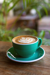 Cup of coffee with latte art on wooden table and morning sunlight with shadow through from window. Beautiful morning.