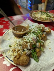A melamine plate full of street food which is a South Asian snack with spice made of tamarind juice, water, egg and other topping are stored in a fried, thin ball.