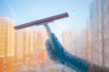 Window washing. Window cleaning with a squeegee and a wiper on a sunny day close-up. Dirty windows.