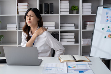 Asian businesswomen suffer from shoulder pain from working too much in an office.