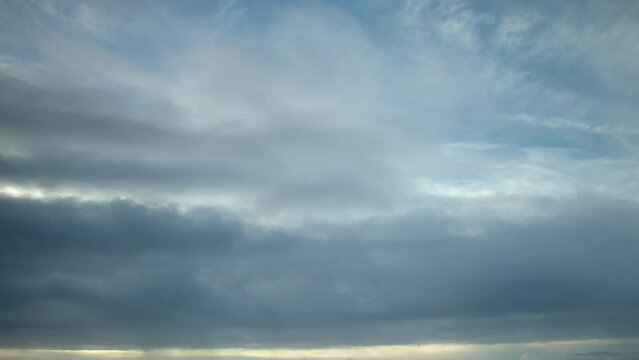 The sky is filled with different types of clouds moving swiftly in a timelapse video.