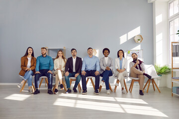 Successful multicultural people men and women posing with office colleagues for team portrait of company employees or participants in business project sit in row in spacious room. Startup culture