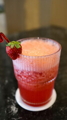 A glass of strawberry juice at the table with a fancy straw.