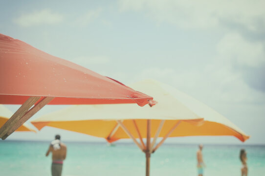Two sun umbrellas on beach with three people in distance, Jamaica