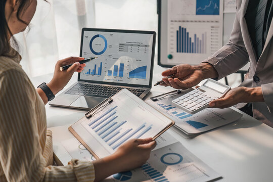 Two business people talk project strategy at office meeting room. Businessman discuss project planning with colleague at modern workplace while having conversation and advice on financial data report.