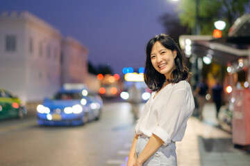 Portrait young beautiful asian woman smiling while travel by the Bangkok street twilight.