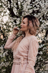 A beautiful woman in a dress near a cherry blossom. Spring Day