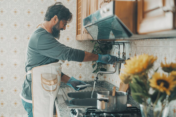 Husband one man washing dishes at home alone smiling and enjoying cleaning housekeeping indoor...